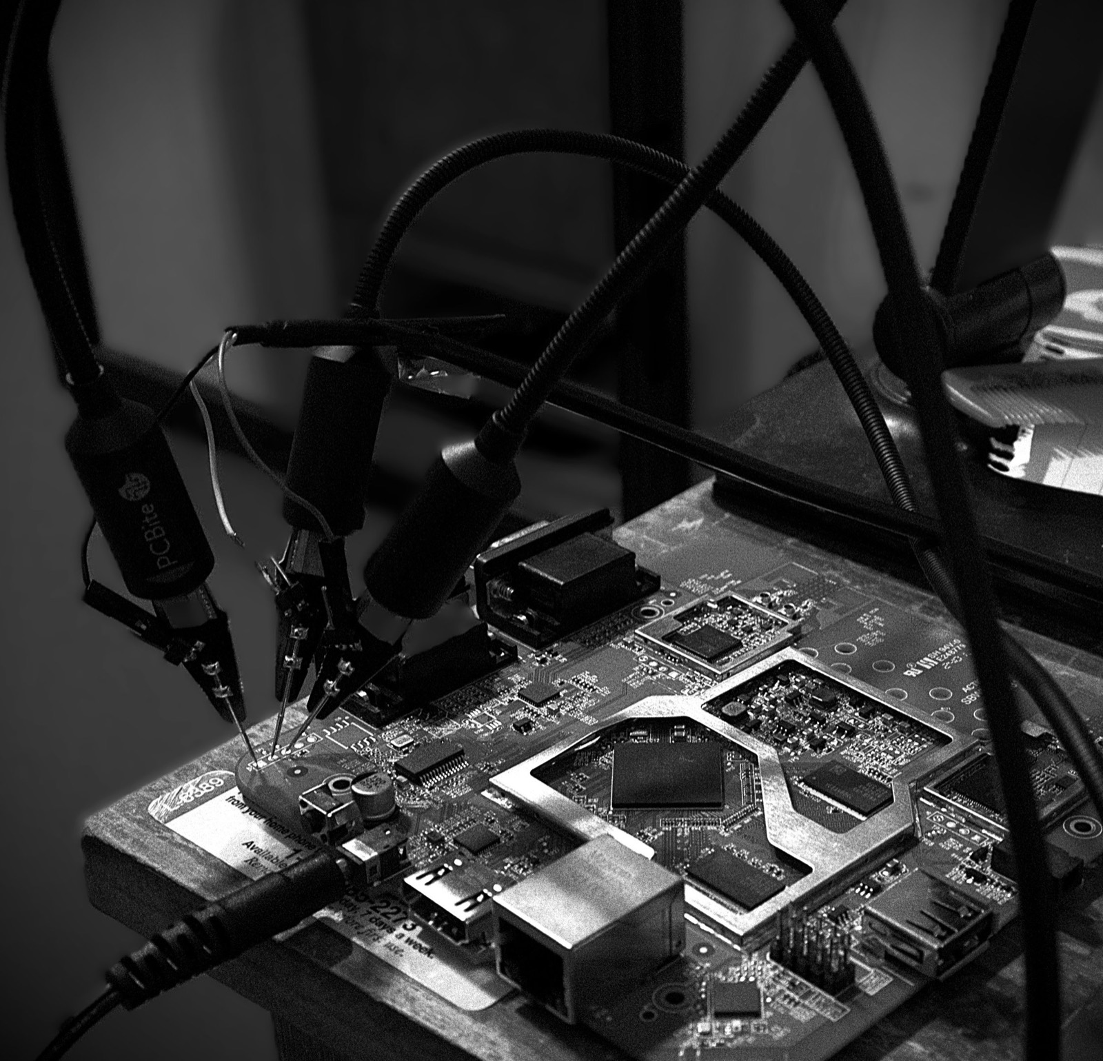 Micro-probes clipped onto the test points of a development board, photographed in black and white.