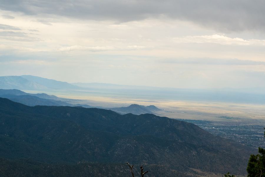 A mountain range falling away to a wide valley under heavy cloud.