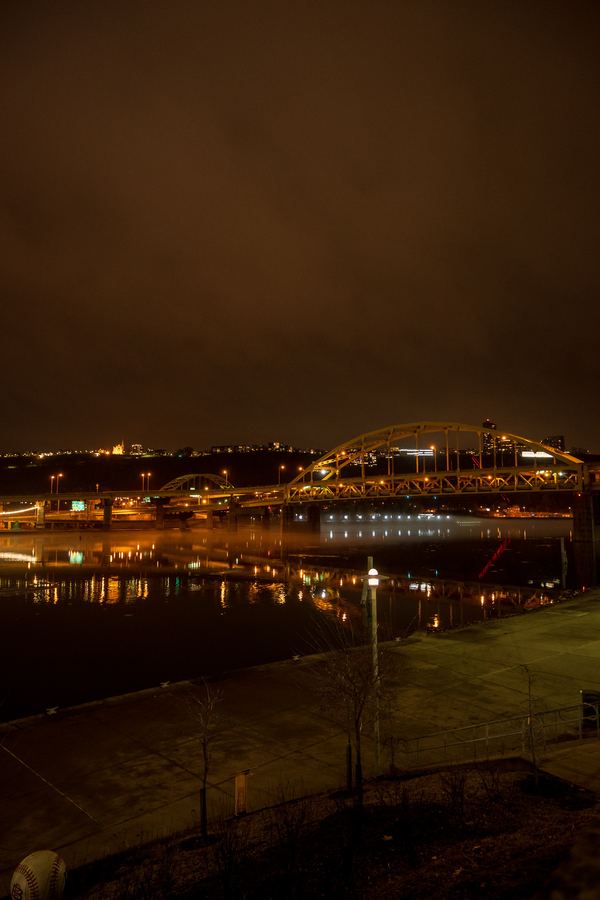 A long exposure of Pittsburgh at night, a lit bridge arcing over the river.